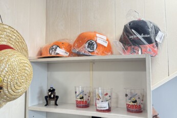 Présentation de divers goodies et accessoires inspirés de mangas, incluant des chapeaux, sacs, figurines et objets de collection, dans une boutique à Cahors.
